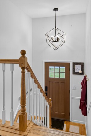 A staircase with wooden balusters and a white handrail, leading to a brown door with a window. A geometric pendant light hangs from the ceiling. - 4-bedroom Village of Dryden house/ 9 mi. to Greek Peak skiing, Cornell, Cortland (Dryden)