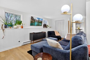Ein modernes Wohnzimmer mit einer großen Couch, einem Fernseher und einer Pflanzenwand.