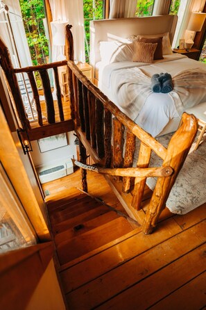 A wooden staircase leading to a bed with a view of greenery outside. - RRG cottage - cave fire pit, hot tub, & pool table (Stanton)