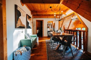 A cozy interior with a wooden ceiling, a dining area with a table and chairs, and a sofa with a patterned cushion. - RRG cottage - cave fire pit, hot tub, & pool table (Stanton)