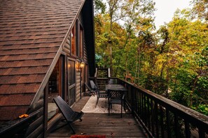 A wooden deck with a railing, a table, and two chairs. - RRG cottage - cave fire pit, hot tub, & pool table (Stanton)