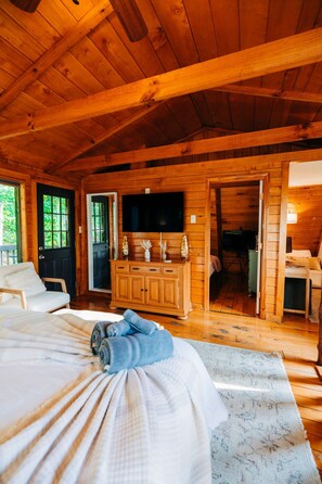 A wooden cabin interior with a bed, a television, and a wooden cabinet. - RRG cottage - cave fire pit, hot tub, & pool table (Stanton)