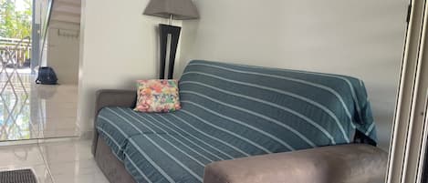 A modern living room with a sofa, a lamp, and a painting on the wall.