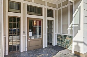A building entrance with a double door, a glass window, and a stone wall.