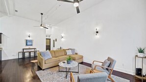 A spacious living area with a sofa, armchairs, a coffee table, and a ceiling fan.