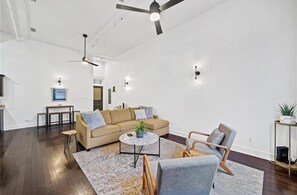 A spacious living area with a sofa, armchairs, a coffee table, and a ceiling fan.