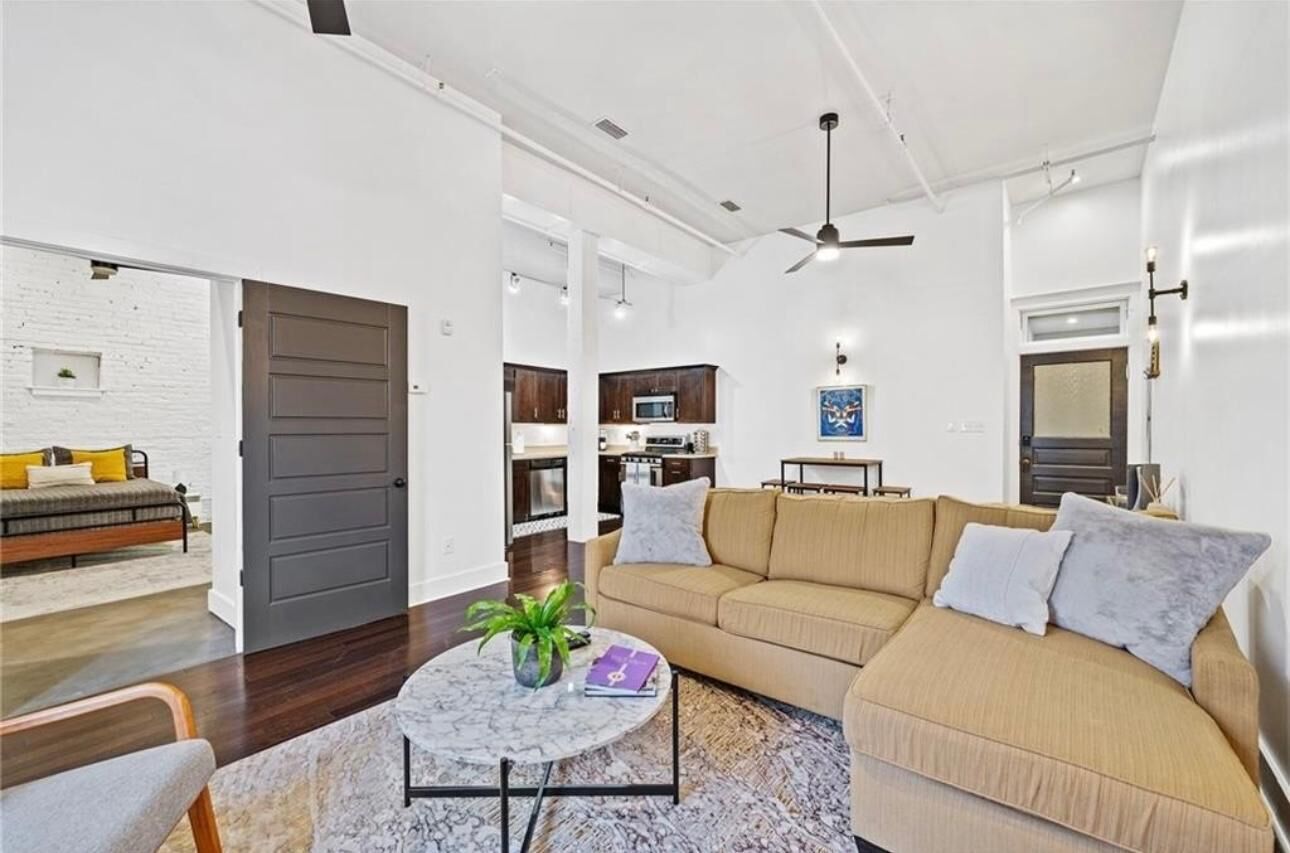 A modern living room with a sofa, coffee table, and a dining area with a microwave.