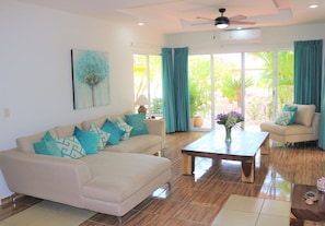 A living room with a sofa, armchairs, a coffee table, and a painting on the wall.