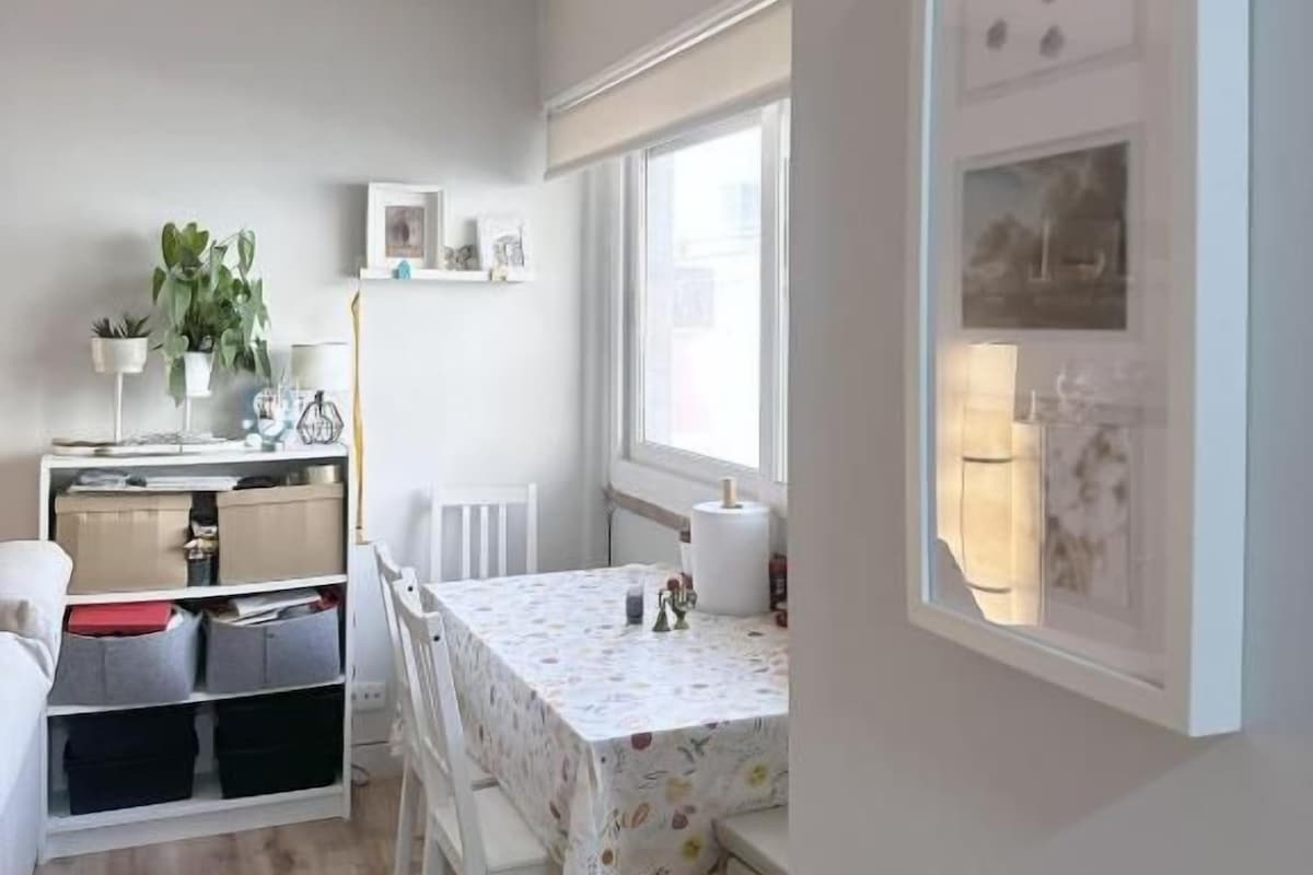 A compact kitchen with white cabinetry, a dining table with chairs, and a window providing natural light.