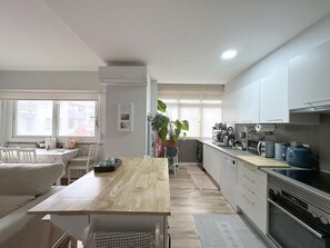Eine moderne Küche mit Holztisch, weißen Schränken und einem großen Fenster.