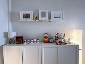 Ein weißes Schränkchen mit Ablagefläche, auf der gerahmte Bilder, eine Uhr und Figuren stehen.