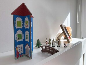 Una repisa con una casita azul en miniatura, un puente y varias figuritas.