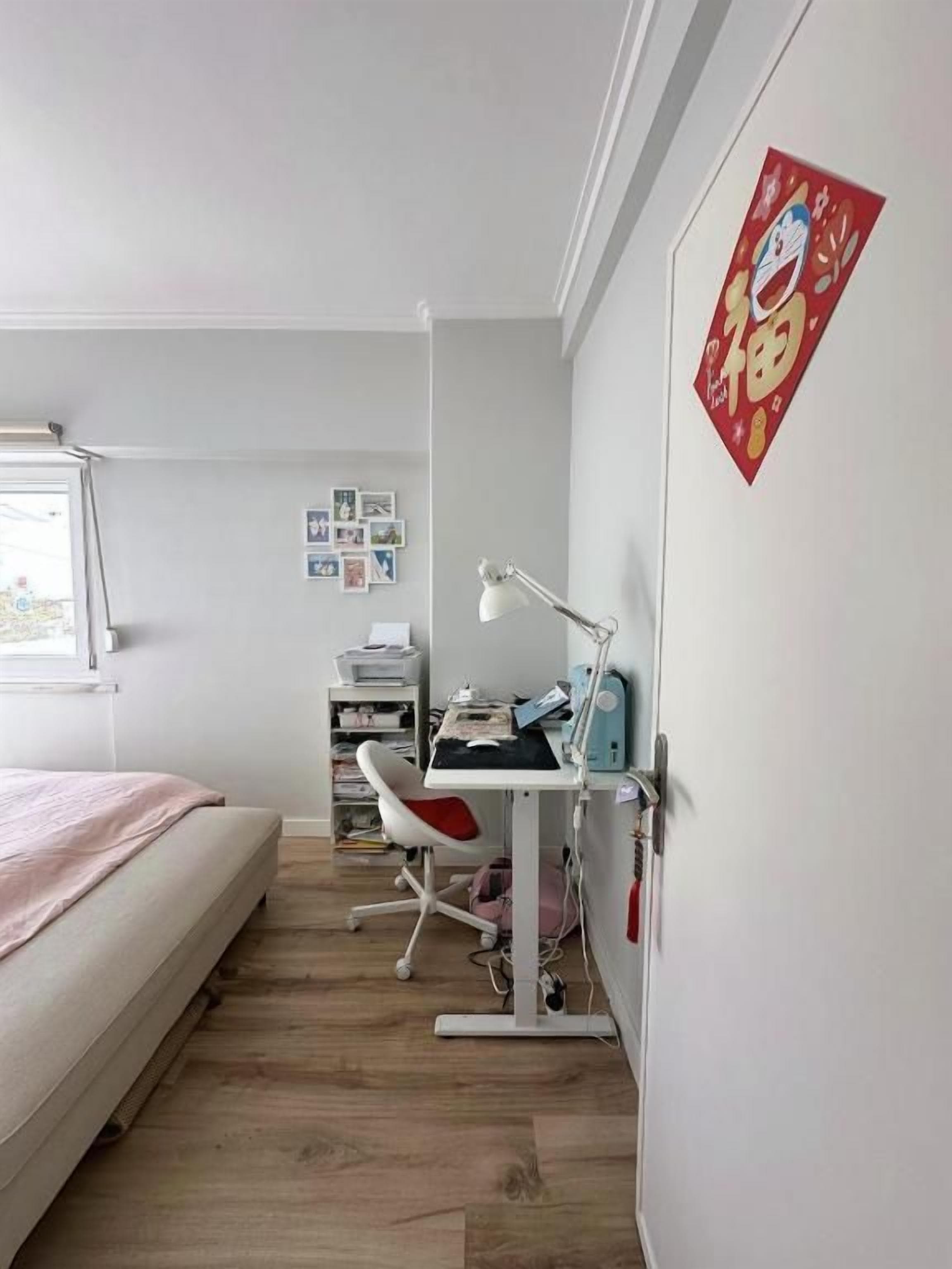 A bedroom with a bed, desk, chair, and a wall-mounted shelf with books.