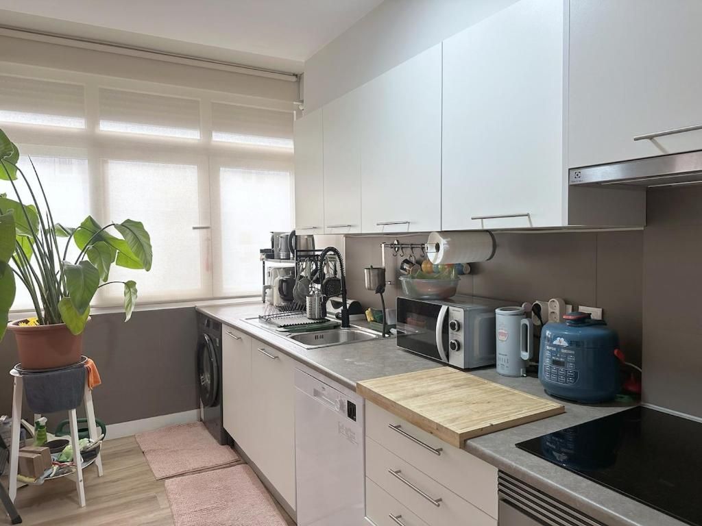 A modern kitchen with a dishwasher, microwave, toaster, and a large blue water dispenser.