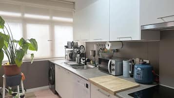 A modern kitchen with a dishwasher, microwave, toaster, and a large blue water dispenser.
