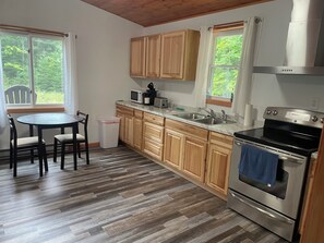 A kitchen with wooden cabinets, a stainless steel stove, a sink, and a dining table with chairs.