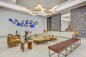A modern living room with a white sofa, wooden coffee tables, and abstract wall art. - Beachfront Cap Cana Estate · Private Beach · Spa (Punta Cana)