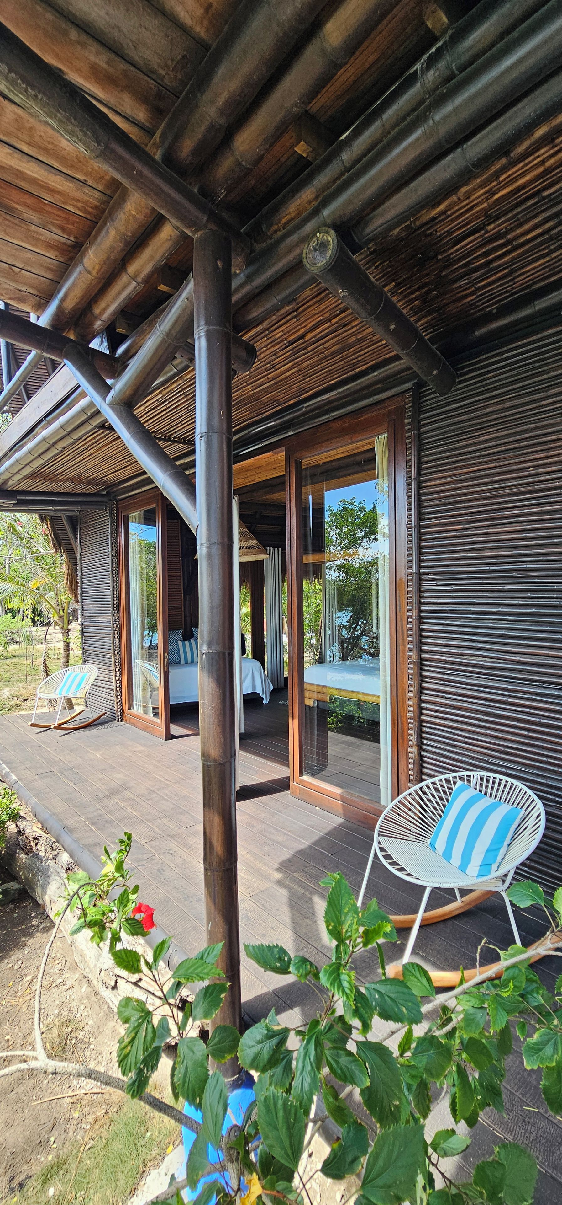 Een houten constructie met een overdekte patio, een bed met uitzicht en een schommelstoel.