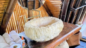A room with a bamboo ceiling, a stone basin, and a basket with towels and toiletries. - ENAI DEL MAR (Bolívar)