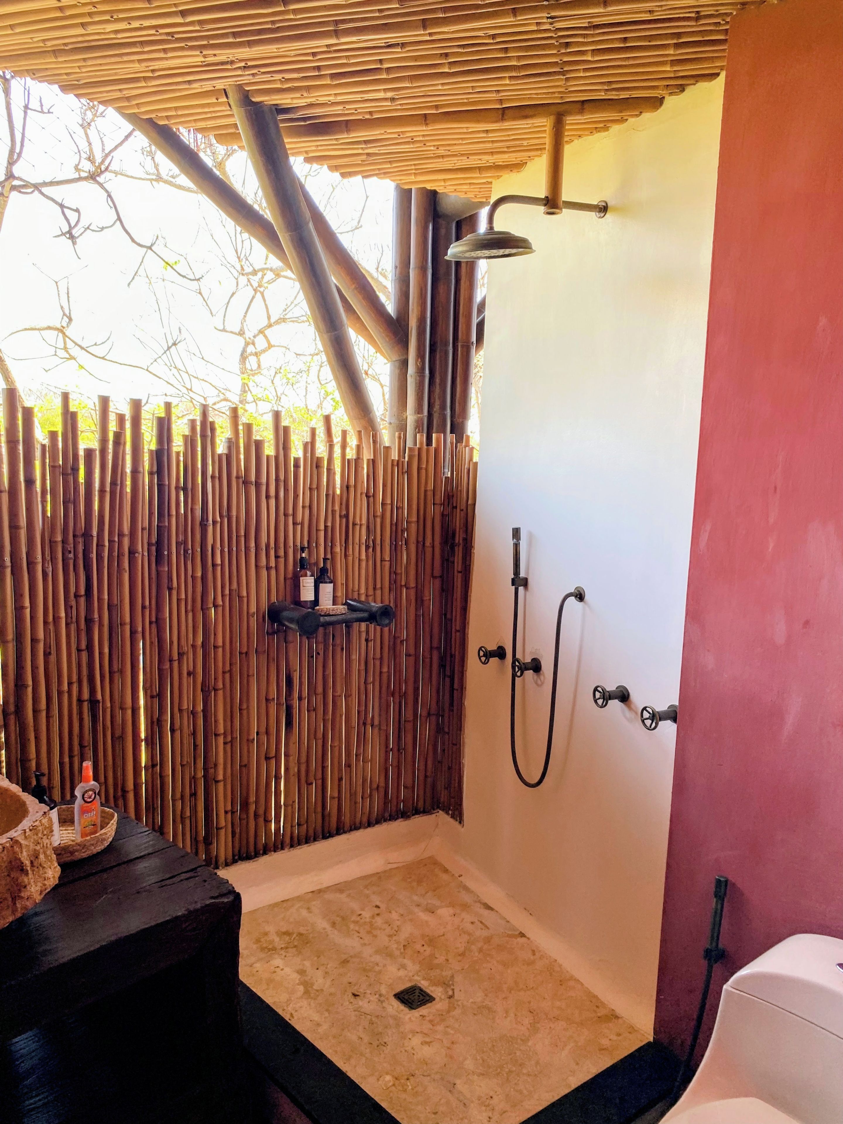 A shower area with bamboo walls, a showerhead, and a hand shower.