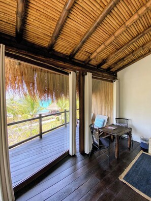 Un espacio exterior cubierto con una terraza de madera, una mesa con sillas y vistas a la vegetación.