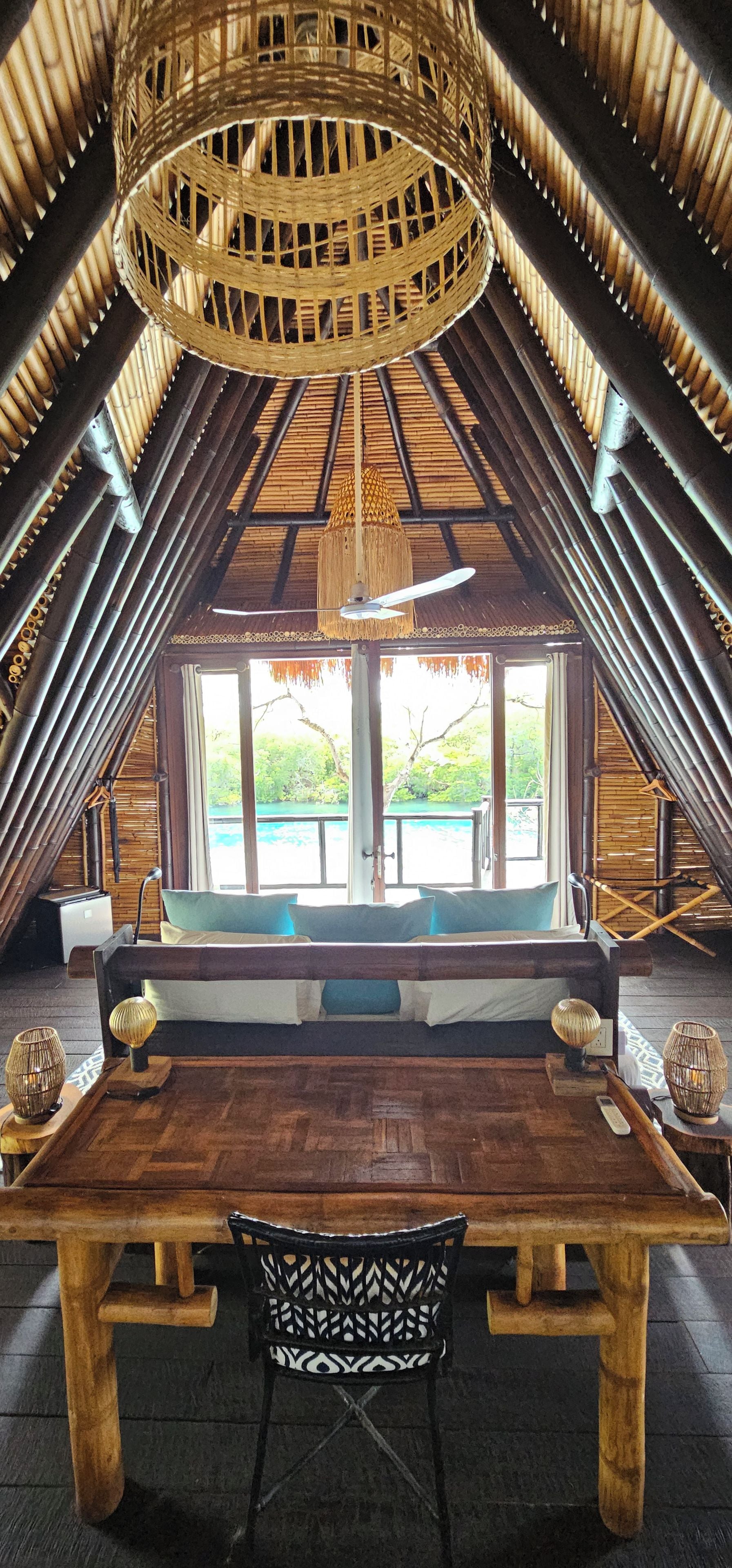 Ein Dachzimmer mit Holztisch, Stuhl und großem Fenster mit Blick auf Grünflächen.