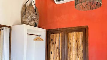 A room with a red wall, a white cabinet, a hanging basket, a door with a bamboo design, and a hanging light fixture.