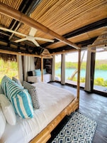 Una habitación con cama, ventilador de techo y vista al mar.