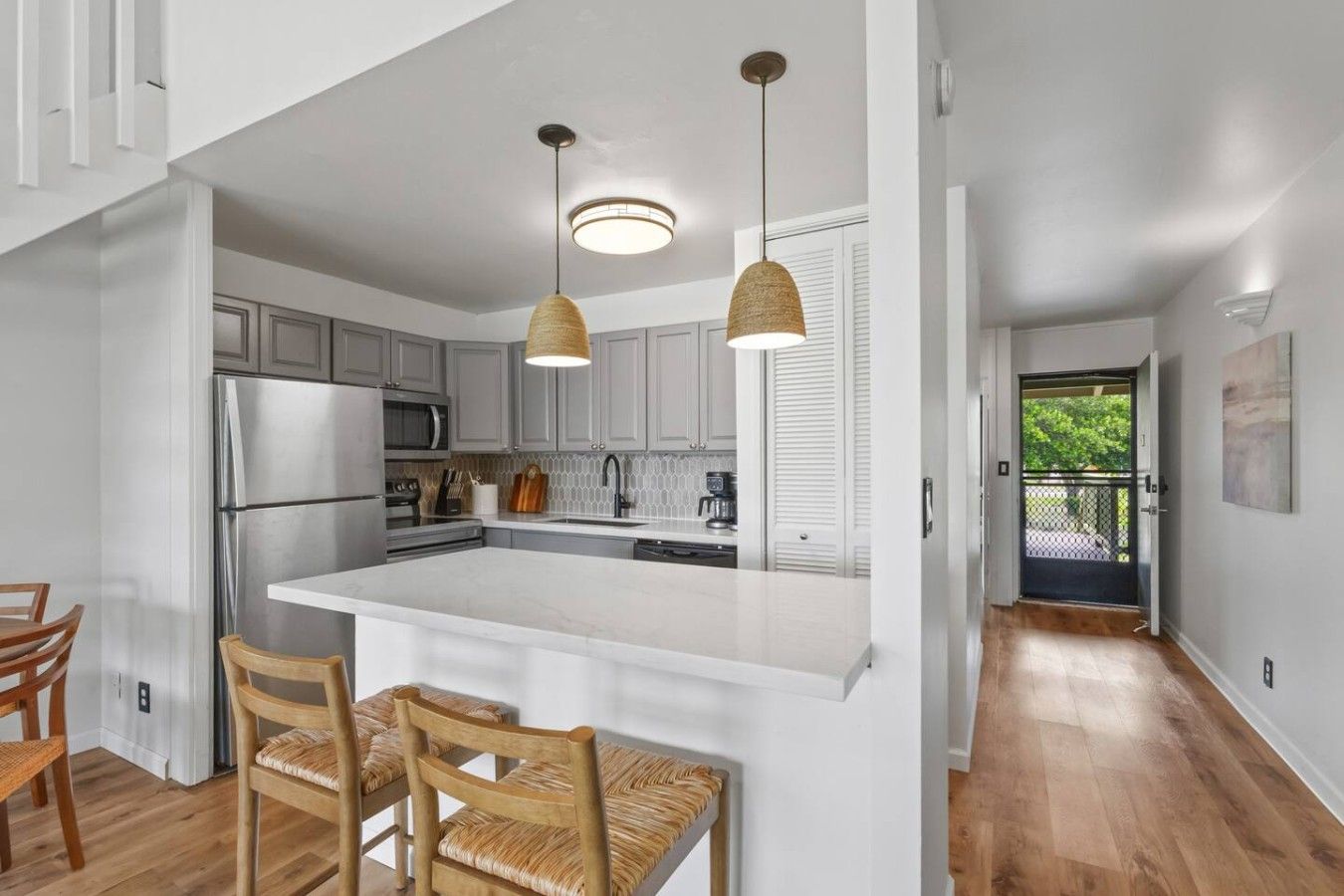 Une cuisine moderne dotée d’un îlot central, de luminaires suspendus et d’un coin repas avec des chaises en bois.