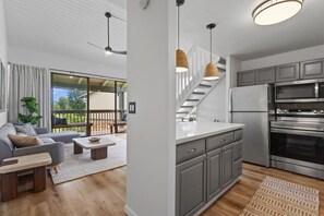 A modern kitchen with grey cabinets, a stainless steel refrigerator, and a built-in oven.