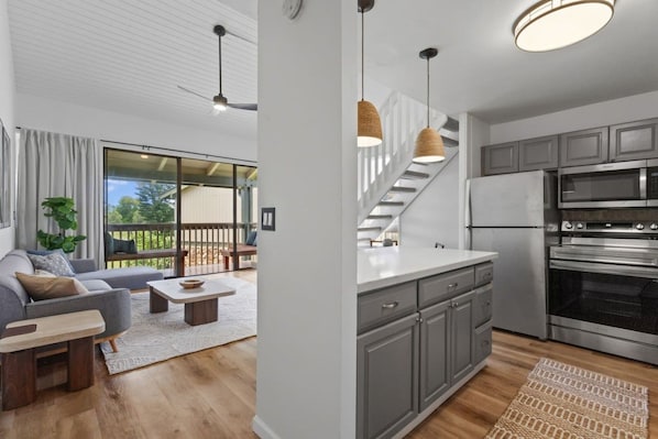 A modern kitchen with grey cabinets, a stainless steel refrigerator, and a built-in oven.