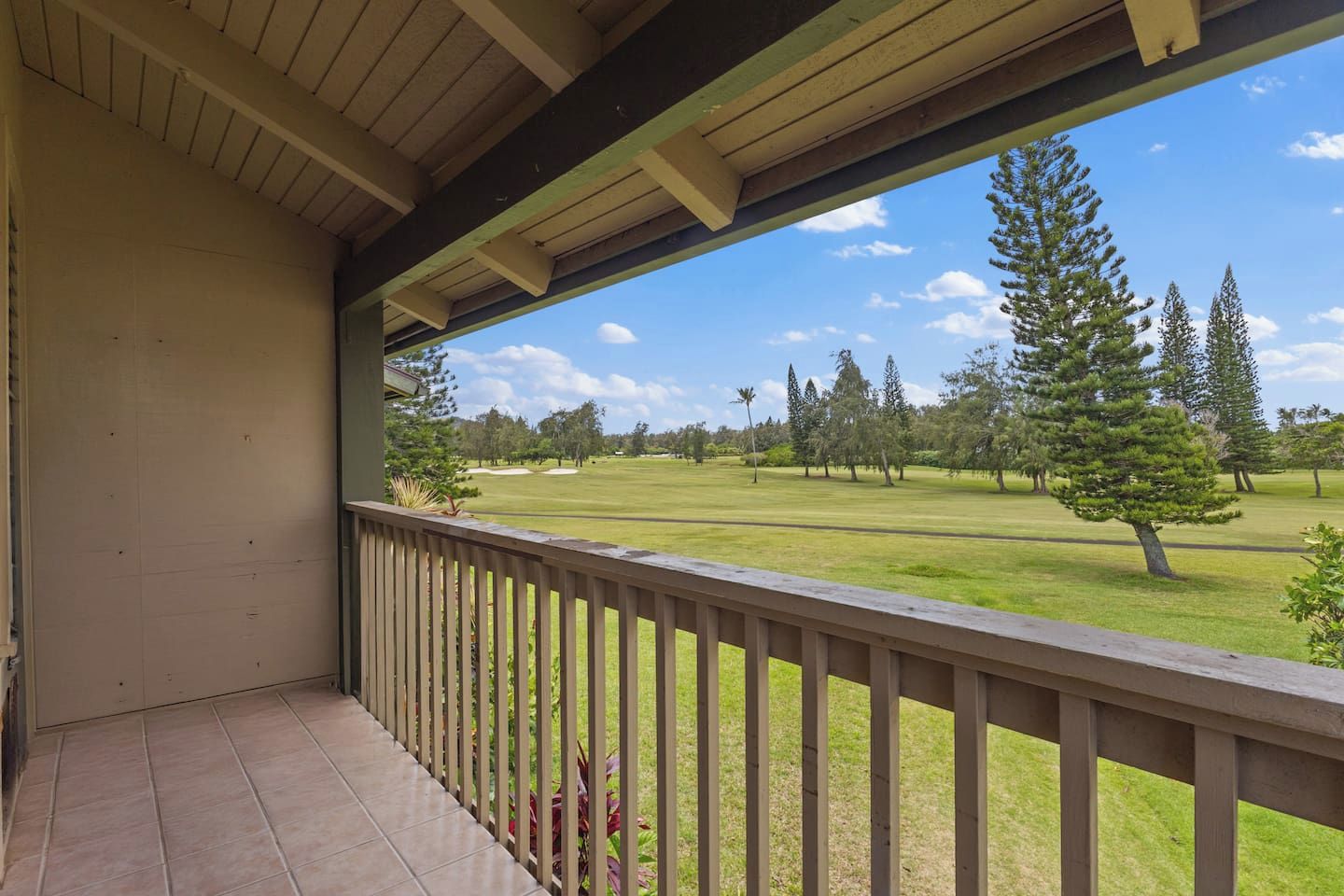 A covered balcony with a view of a golf course.