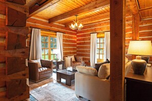 A log cabin interior with a fireplace, leather sofas, and a chandelier. - Ninemile Creek Cabin: Fish in back yard, Hot Tub (Huson)