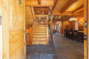 A wooden interior with a staircase leading to a second floor, stone flooring, and a dining area with chairs and a table. - Ninemile Creek Cabin: Fish in back yard, Hot Tub (Huson)