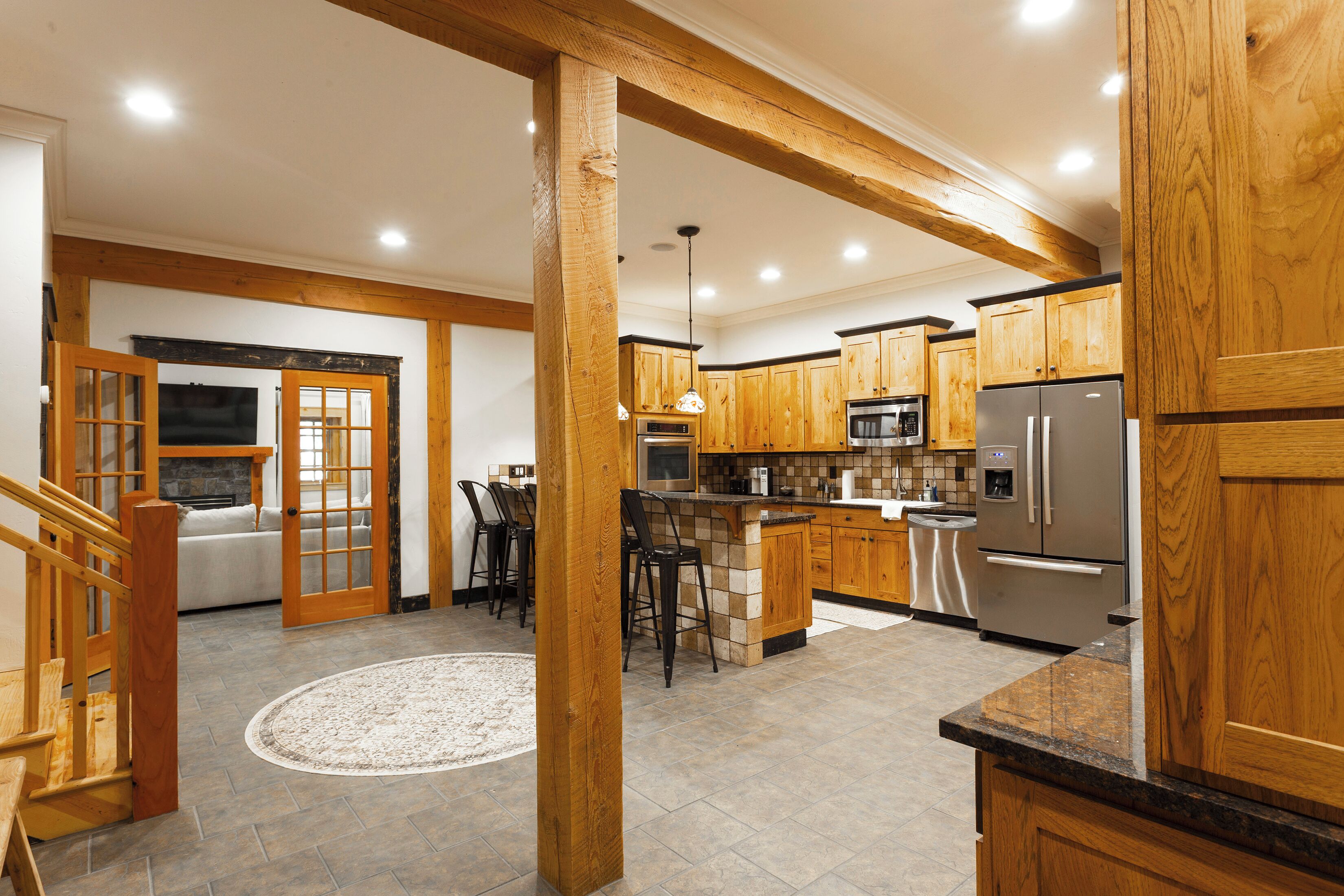A kitchen with wooden cabinets, a stainless steel refrigerator, and a dining area with a table and chairs.
