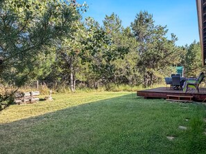 Ein Garten mit Holzterrasse, Gartenmöbeln und einem Rasen.