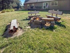 A wooden bench, a stone fire pit, and a house in the background. - Donnelly Mountain Retreat | Games, Wood Stove & Fire Pit (Donnelly)