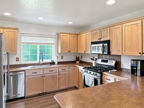 A modern kitchen with wooden cabinets, stainless steel appliances, and a large window. - Donnelly Mountain Retreat | Games, Wood Stove & Fire Pit (Donnelly)