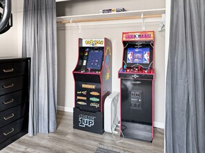 Two arcade machines, Pac-Man and NBA JAM, in a room with a black dresser and grey curtains. - Donnelly Mountain Retreat | Games, Wood Stove & Fire Pit (Donnelly)