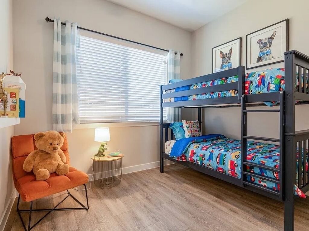 A child's bedroom with bunk beds, a teddy bear, and a lamp.