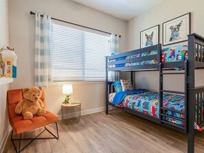 Ein Kinderzimmer mit Etagenbetten, einem Teddybären und einer Lampe.