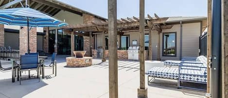Un patio al aire libre con arreglos de asientos, una parrilla y una pérgola.