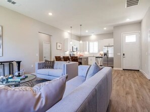 A modern living room with a sofa, coffee table, and a dining area with chairs. - 1 -3-bedroom Single Family Residence house in perfect Oklahoma City (Oklahoma City)