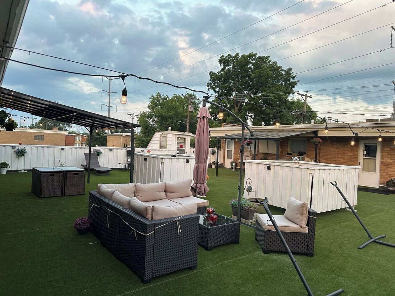 An outdoor patio area with a covered seating area, artificial grass, and a pool.