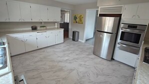 A kitchen with white cabinets, a stainless steel refrigerator, and an oven.