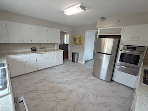 A kitchen with white cabinets, a stainless steel refrigerator, and an oven.