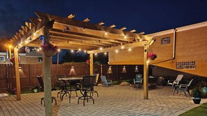 An outdoor patio with a pergola, seating area, and a brick floor. - The Rooftop - Haven! (Waukegan)