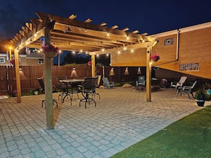 An outdoor patio with a pergola, seating area, and a brick floor. - The Rooftop - Haven! (Waukegan)