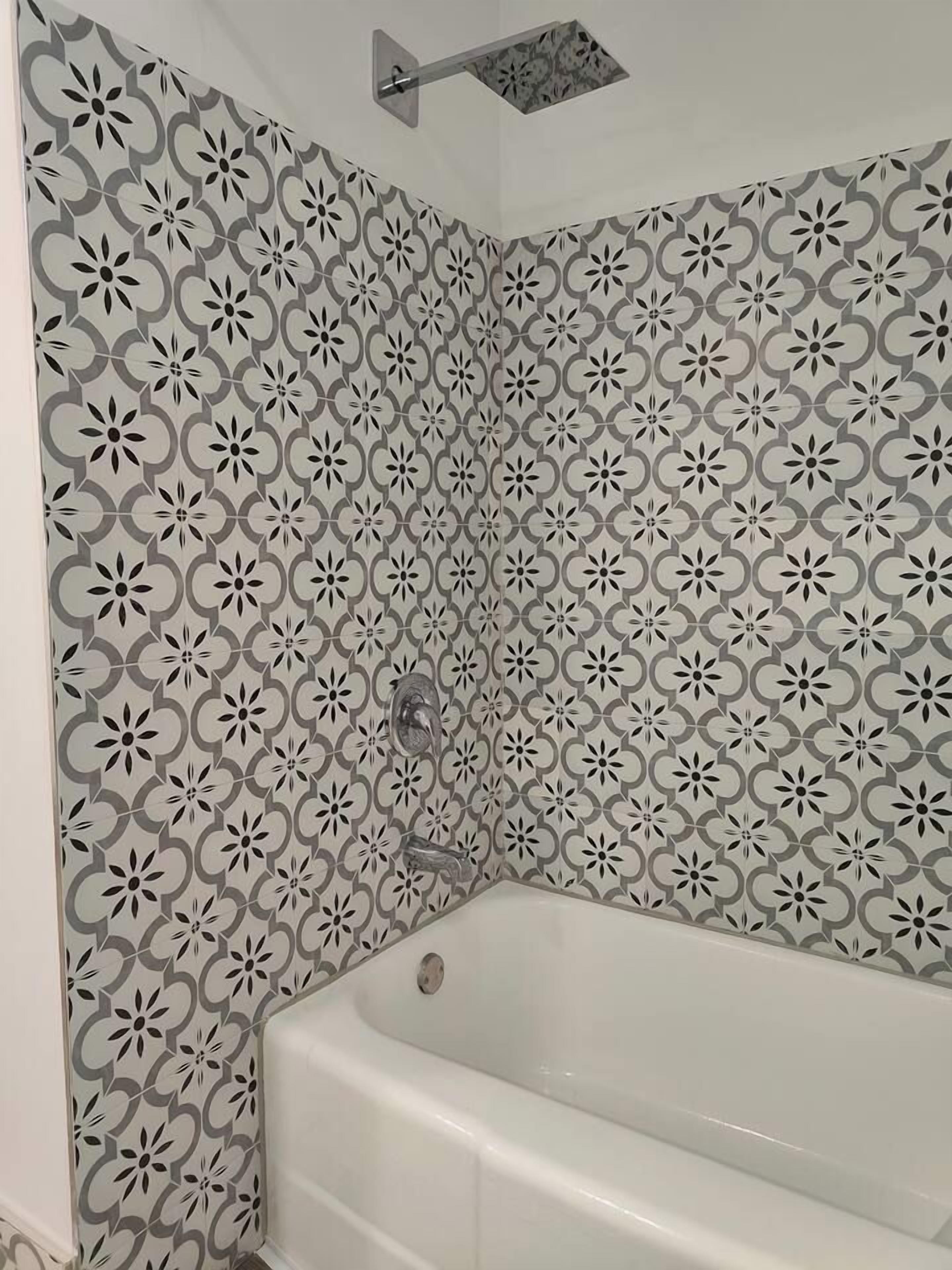 A bathroom with a white bathtub, a showerhead, and a patterned wall.