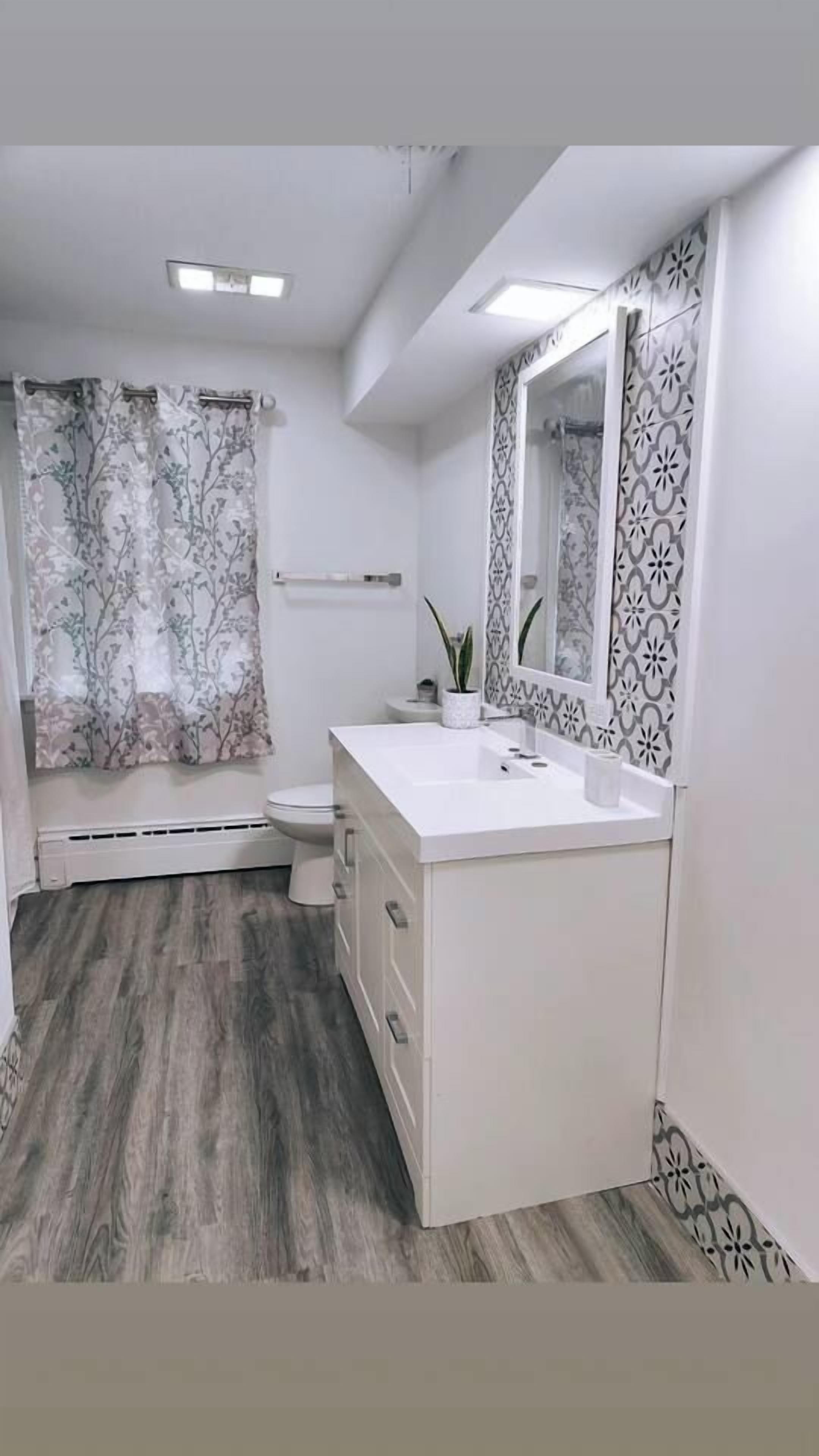 Une salle de bain avec un lavabo blanc, un miroir et des toilettes.
